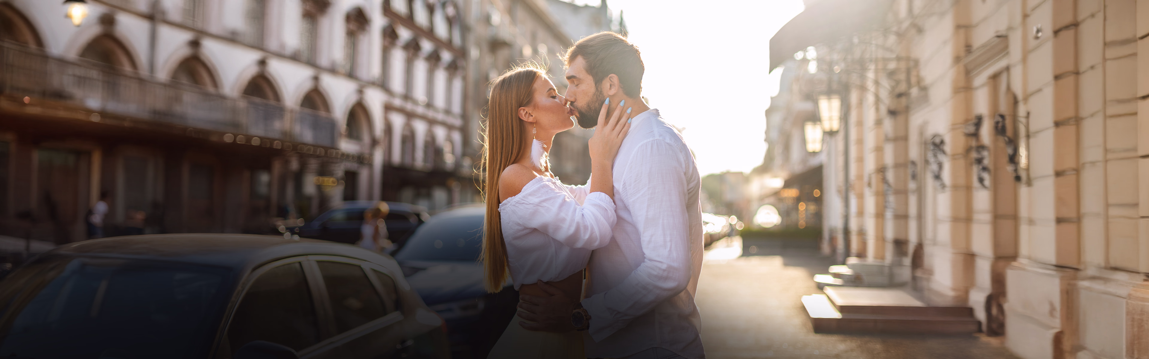Paar küsst sich in einer lichtdurchfluteten Straße, Symbol für Liebe und emotionale Verbindung